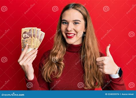 Young Blonde Woman Holding 5000 Hungarian Forint Banknotes Smiling Happy And Positive Thumb Up