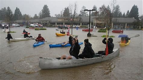 People Use Kayaks And A Canoe To Make Their Way Around A Flooded