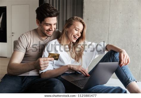Photo Of Young Happy Loving Couple In Home Indoors On Sofa Using Laptop