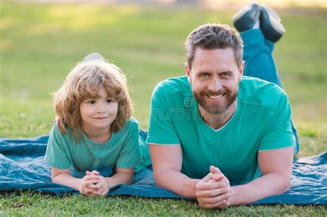 Father And Son Laying On Grass In Park People Having Fun Outdoors Concept Of Happy Vacation