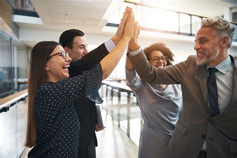 Business Team High Fiving Each Other In An Office Stock Photo