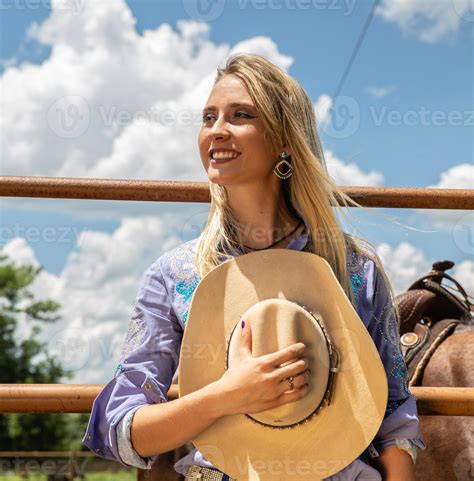 belle cow girl blonde avec chapeau debout près de l arrière plan du ranch de chevaux 9349021