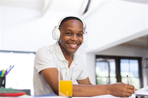 Happy African American Teenage Boy With Headphones Sitting At Desk
