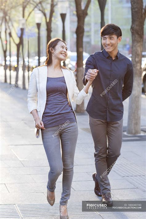 Chinese Couple Holding Hands While Walking On Sidewalk Bonding