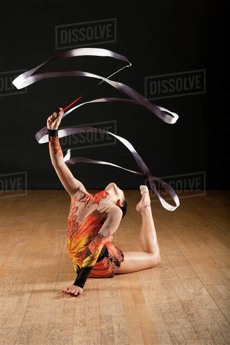 Gymnast Bending Backwards On Floor Twirling Ribbon Stock Photo
