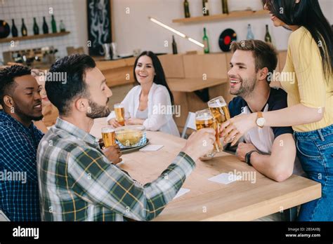 Cheerful Multicultural Friends Talking While Drinking Beer In Pub Stock