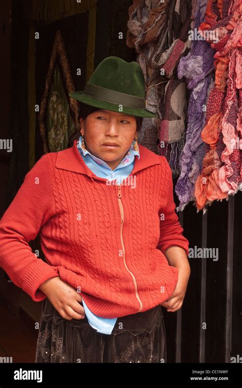 an indigenous ecuadorian woman stands in the doorway of her store across from the central market