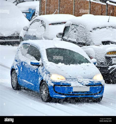 Travel Scene Blue Car Covered In Snow Headlights On Driving In Bad