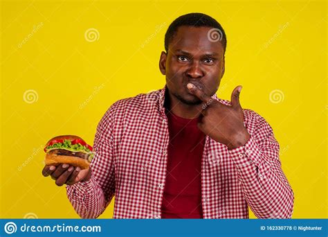 Joven Afroamericano Comiendo Hamburguesa Aislado De Fondo Amarillo