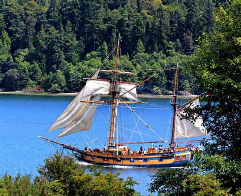 An Old Sailing Ship In The Middle Of A Body Of Water With Trees Around It