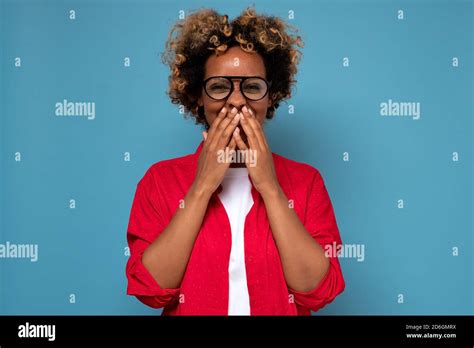 african american woman with curly hair laughing and embarrassed giggle covering mouth with hands