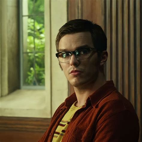A Man With Glasses Sitting In Front Of A Window Looking Off To The Side