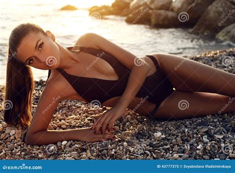 有黑发的性感的女孩在摆在日落海滩的比基尼泳装 库存图片 图片 包括有 晒黑 照亮 棕褐色 魅力 日落 43777375