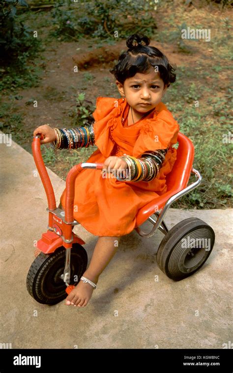 Young Indian Girl In Orange Dress With Armful Of Bangles Riding A