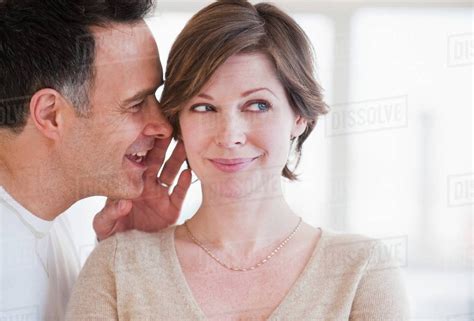 Man Whispering To Womans Ear Stock Photo Dissolve