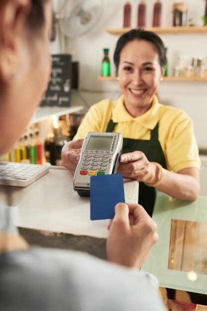 premium photo cheerful mature barista giving card reader to customer paying for the order