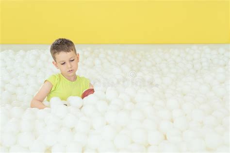 Happy Child Boy In The Big Dry Pool With Thousand Of White Balls