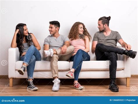 Portrait Of Young Group Of Friends Sitting On A Sofa In A Studio