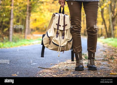 Woman With Backpack Wearing Hiking Boots Is Standing On Road In Autumn Forest Travel Concept