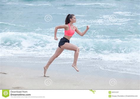 Woman Running On The Beach At Cloudy Morning Side View Stock Image