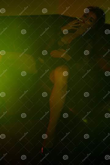 Woman Wearing Black Lingerie Sitting On The Sofa In Green Light Stock