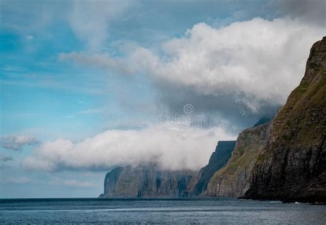 Large Cliff Surrounded By The Water Under The Clouds Stock Photo