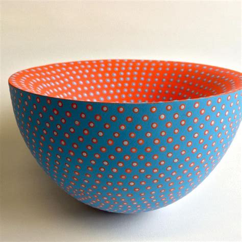 An Orange And Blue Polka Dot Bowl On A White Surface
