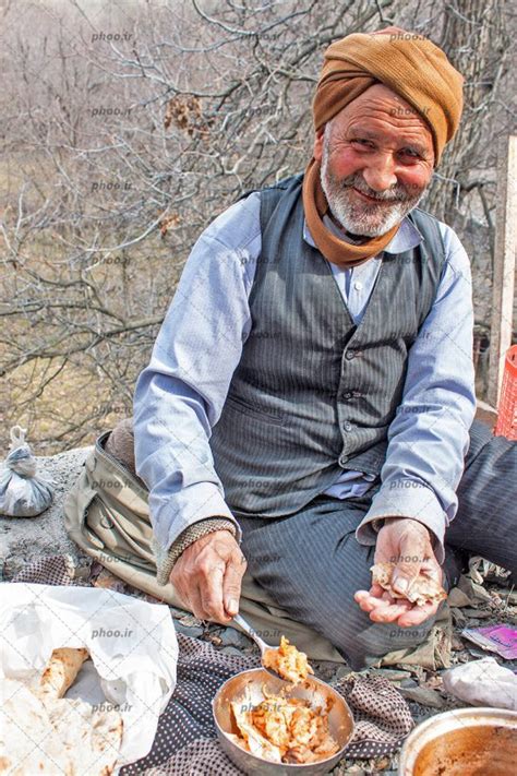 عکس با کیفیت چهره ی دلنشین پیر مرد روستایی با لبخند زیبا در حال خوردن