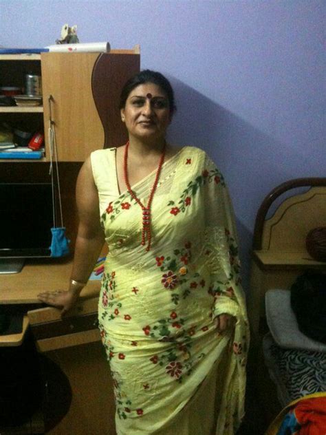 A Woman In A Yellow Sari Standing Next To A Desk