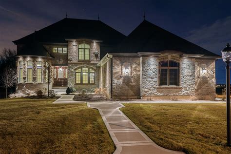 a large brick house lit up at night with lights on the front and side