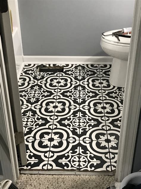 A Bathroom With A Toilet And Black And White Tile Flooring In Its Corner