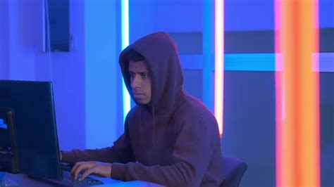 African Hacker Dressed In Hoodie Working On The Computer By Stock24