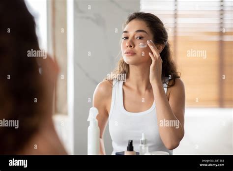 Femme Appliquant De La Crème Hydratante Faciale Sur Le Visage Dans La