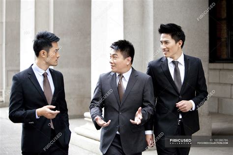 Chinese Businessmen Walking And Talking On Street — Side By Side