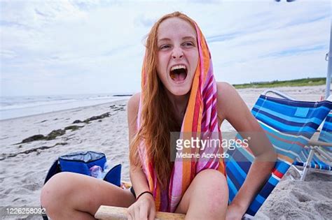 Portrait Of A Teenage Girl At The Beach Laughing Really Hard With A Striped Towel Over Her Head