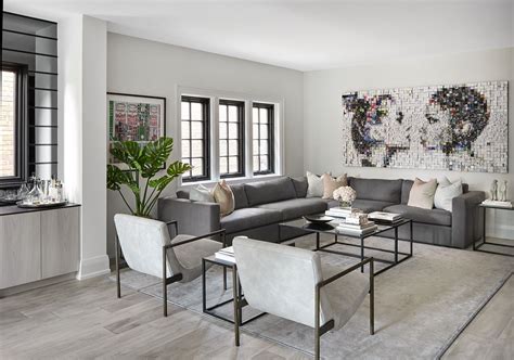 A Living Room With Grey Couches And White Chairs In Front Of A Large