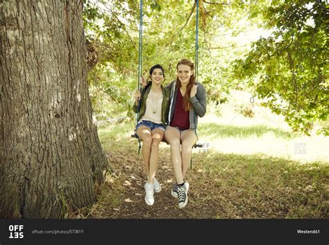 Two Best Friends Sitting Together On A Swing Stock Photo Offset