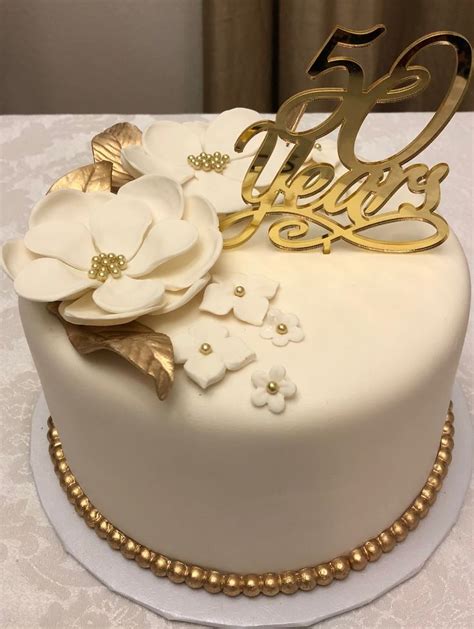 A White And Gold 50th Birthday Cake With Flowers