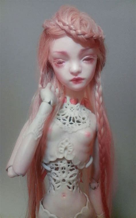 A Close Up Of A Doll With Long Hair And Pink Hair Wearing A White Top