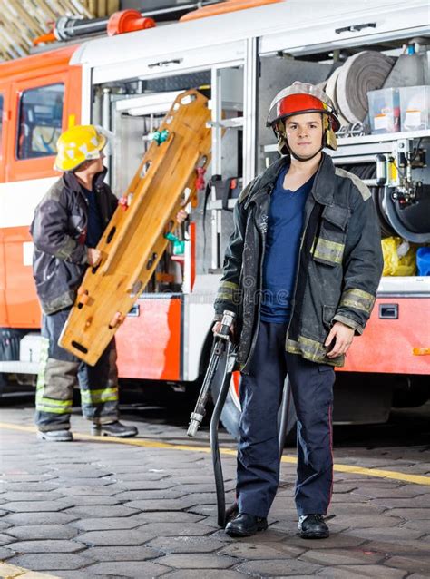 Firefighter Holding Hose While Colleague Carrying Stock Image Image