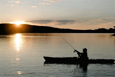 Unrecognizable Fisherman In Boat Fishing On Lake At Sunset · Free Stock