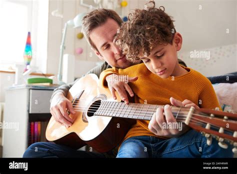 Single Father At Home With Son Teaching Him To Play Acoustic Guitar In