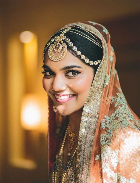 a woman in a bridal outfit smiles for the camera while wearing a veil and headpiece