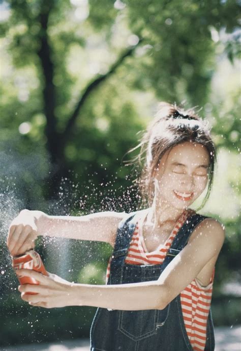 A Woman Is Spraying Water On Herself With Her Hands And Smiling At The