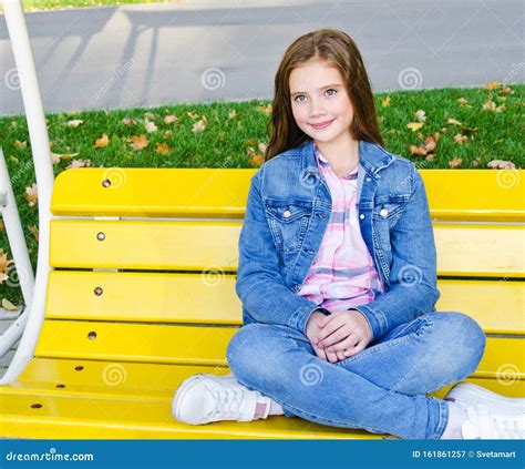Portrait Of Adorable Smiling Little Girl Child Sitting In The Park