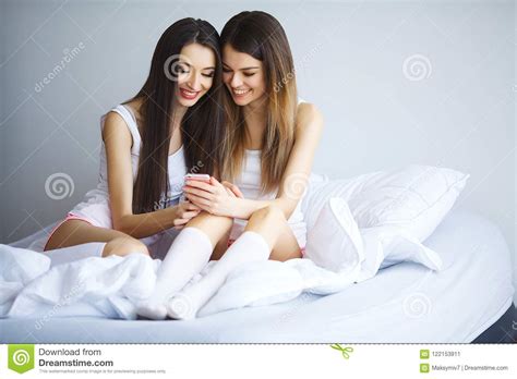 Two Hot Girls Lying On A Bed Taking A Photo Of Themselves Stock Image