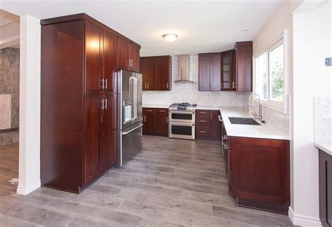 Void door cabinets were also used in part of the kitchen to display cookbooks and other objects. gray wood floors, warm cherry cabinets, white counters ...