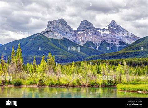 Canmores Famous Three Sisters Mountain Peaks Beside The Bow River In