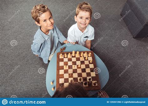 High Angle View Of Little Boys Playing Chess And Smiling At Camera