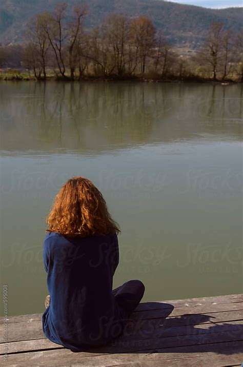 Redhead Girl From The Back Sitting On The Dock Looking In The River